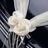 Detailansicht zweier cremefarbener Rosenblüten aus Satinoptik mit transparentem Organza und dekorativen Schleifenbändern auf einer glänzenden Motorhaube. Produktbild-Vorschau