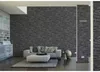 A living room with a stone-effect wallpaper, sofa, and ottoman. Náhľad obrázku produktu
