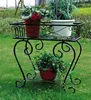 A black metal plant stand with three potted plants on a grassy lawn. Produktbild-Vorschau