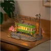 A miniature diorama of a train station with a green train, cherry blossom trees, and streetlights. Produktbild-Vorschau
