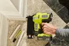 A hand is holding a Ryobi cordless nail gun next to some trim molding and a marker. Anteprima dell’immagine prodotto