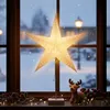 A lit paper star lantern sits on a windowsill in front of a snowy window, with a small reindeer figurine and festive decorations. Produktbild-Vorschau