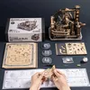 A flat lay of a ROKR 3D wooden puzzle marble run kit, including the box, unassembled wooden pieces, clear plastic components, instructions, and a partially assembled model. Podgląd zdjęcia produktu
