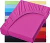 A pink fitted sheet is displayed diagonally in the foreground, with a stack of other colored fitted sheets visible in the background. Produktbild-Vorschau