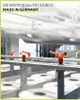 A close-up view of industrial machinery with orange levers and white rolls of paper. Produktbild-Vorschau