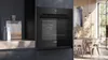 A modern kitchen with a built-in oven and dining area in the background. Produktbild-Vorschau