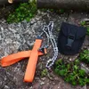 A portable hand chainsaw and its carrying pouch are laid out on a rocky surface with some greenery. Náhled obrázku produktu