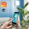 A person is using a smartphone to control a smart device mounted on a wall, with a plant in the background. Náhled obrázku produktu