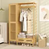 A bamboo wardrobe rack with clothes hanging on it, placed in a bedroom setting next to a bed. Podgląd zdjęcia produktu