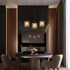A modern dining room with a round table, chairs, and a set of three pendant lights hanging above. Produktbild-Vorschau