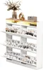 A white shoe cabinet with multiple flip-down drawers and an open shelf on top, decorated with a vase of flowers and a decorative object. Náhľad obrázku produktu