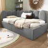 A child's bedroom with a grey upholstered bed, decorated with pillows and blankets. A rug with a cartoon animal face is on the floor. Produktbild-Vorschau