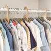 A close-up view of baby clothes organized on hangers in a closet, with wooden size dividers. Produktbild-Vorschau