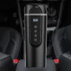 A black electric travel mug is placed in the center console of a car, between the seats. Podgląd zdjęcia produktu