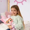 A young girl is holding a doll in a bunny outfit while sitting on a bed. Anteprima dell’immagine prodotto