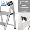 A close-up view of a silver aluminum step stool, highlighting its safety features and brand. Produktbild-Vorschau