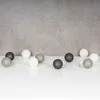 A string of decorative LED lights with spherical lamps in various shades of gray and white, arranged on a white surface against a textured gray wall. Produktbild-Vorschau