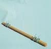 A wooden bar with metal clamps and hooks, laid diagonally on a light blue background. Produktbild-Vorschau