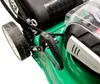 A close-up view of a green lawnmower's handle and wheel. Produktbild-Vorschau