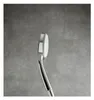 A close-up side view of a chrome and white hand shower head against a gray tiled wall. Produktbild-Vorschau