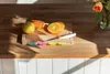 A cutting board with oranges and a knife on a wooden countertop, with sunlight casting shadows. Anteprima dell’immagine prodotto
