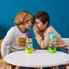 Two young boys are whispering secrets to each other over a table with two water bottles. Náhled obrázku produktu