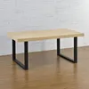A wooden table with black metal legs is displayed against a white brick wall. Náhled obrázku produktu