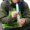 A person is using a portable water filter straw to filter water into a bottle. Produktbild-Vorschau
