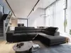 A modern living room with a large sectional sofa, a coffee table, and a dining area in the background. The room has high ceilings and large windows with sheer curtains. Produktbild-Vorschau