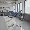 A blue electric bicycle is mounted on a repair stand in a workshop. Voir les images du produit