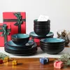 A collection of tableware and gift boxes arranged on a wooden table, with some festive greenery. Voir les images du produit