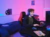 A young person is playing a video game in a room with colorful lighting. Voir les images du produit