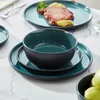A set of teal and black ceramic dishes, including a bowl and plates, arranged on a marble-like surface. A plate with steak and potatoes is visible in the background. Náhled obrázku produktu