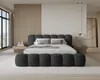 A modern bedroom with a large upholstered bed. Voir les images du produit
