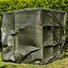 A green tarp covering an object, placed on grass with a hedge in the background. Produktbild-Vorschau