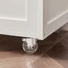 Close-up of the caster wheels of a white furniture item on a wooden floor. Produktbild-Vorschau