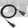 A black USB programming cable with a dual-pin connector for a walkie-talkie, shown against a blurred background of two walkie-talkies. Náhled obrázku produktu