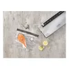 A vacuum sealer machine with a bag of salmon and cooking ingredients on a concrete surface. Podgląd zdjęcia produktu