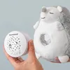 A hand holds a white projector device next to a plush hedgehog toy. Voir les images du produit