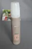 A bottle of hairspray is placed on a gray surface, with a blurred magazine in the background. Produktbild-Vorschau