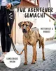 A person holding a dog leash with a dog standing on a cobblestone street. Produktbild-Vorschau