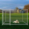 A dog is lying inside a metal dog kennel in a grassy field with a house in the background. Náhled obrázku produktu