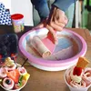 A person is making rolled ice cream on a frozen plate, with berries and finished ice cream cups nearby. Podgląd zdjęcia produktu