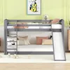 A gray bunk bed with a slide and ladder, decorated with pillows and a teddy bear, in a child's room. Produktbild-Vorschau