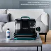 A portable carpet cleaner and a bottle of cleaning solution are placed on a coffee table in front of a sofa. Produktbild-Vorschau
