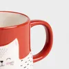 Close-up of a red mug with a white cat design. Produktbild-Vorschau