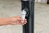 A hand is shown turning a valve on a black outdoor shower. Produktbild-Vorschau