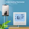 A smart heating thermostat is shown connected to a heating boiler, with a digital display showing temperature and time. Green leaves are in the foreground. Podgląd zdjęcia produktu
