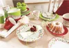 A table setting with a cake, plates, cups, and bowls, decorated with flowers. Produktbild-Vorschau