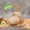 Two pinecone-shaped bird feeders are displayed on a burlap cloth, with a small wooden scoop of sunflower seeds and a decorative flower nearby. A logo is visible in the upper left corner. Produktbild-Vorschau
